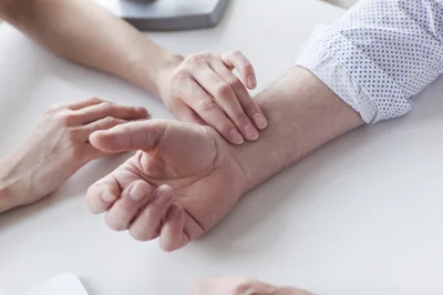 TCM practitioner taking a patient's radial pulse at the wrist using three fingers